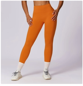 Detail view of bright orange high-waisted yoga pants showing seamless fabric and fit