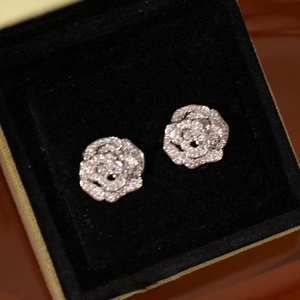 Détail des boucles d'oreilles camélia serties de cristaux dans un écrin en velours noir