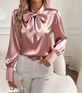 Dettaglio della camicia in raso oro rosa con scollo a fiocco e maniche a lanterna