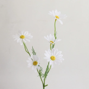 Close-up of artificial white chamomile bouquet with realistic yellow centers and green leaves
