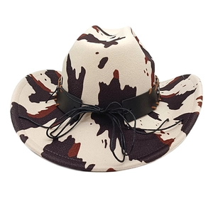 Close-up of cow print felt cowboy hat featuring a black leather band and stitched detail
