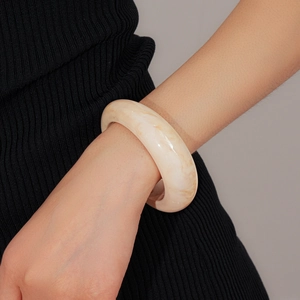 Macro detail of cream resin bangle with marble texture on model's wrist with high gloss