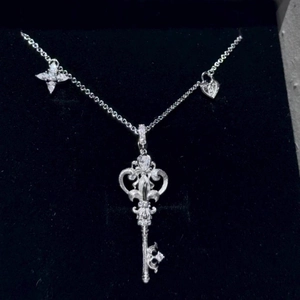 Macro detail of a stainless steel key pendant necklace with star and heart charms.