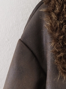 Macro detail of the brown faux suede jacket featuring thick plush faux fur collar textures
