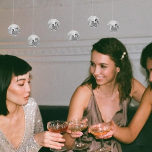 Silver disco mirror balls hanging in a vintage party setting with people celebrating