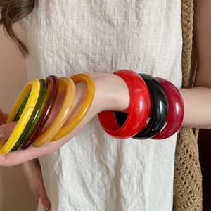 Close-up of colorful resin bangles in yellow, green, and amber on model's wrist