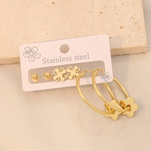 Close-up of golden stainless steel star, flower earrings on a textured stone surface