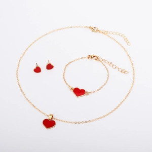 Detailed view of red heart pendant necklace and earring set in polished gold finish
