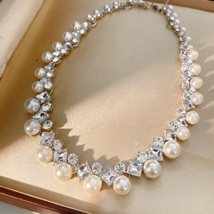 Detail of pearl and diamond-encrusted necklace inside a luxury beige silk jewelry box
