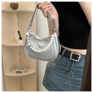Detail of silver crescent bag with 3D heart relief and large pearl chain accessory