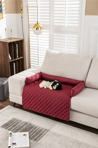 Detail of red quilted pet sofa protector with raised bolsters on a modern couch