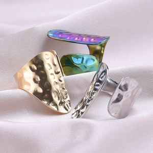 Detail of three hammered stainless steel open rings in gold, silver, and rainbow colors