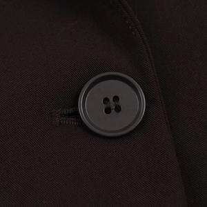 Détail en gros plan du tissu en sergé foncé et d'un bouton noir classique sur un blazer