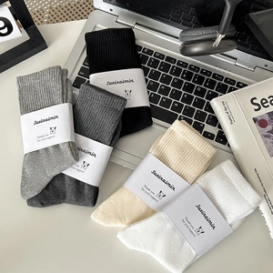 Men's cotton crew socks set in white, grey and beige arranged on a modern desk