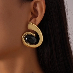 Détail de boucles d'oreilles spirales dorées rétro avec pierre noire ovale incrustée