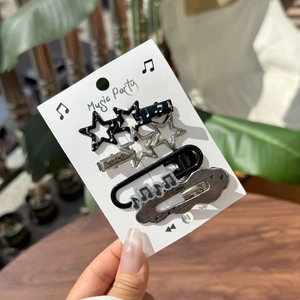 Detail of music-themed hair clips set with stars and music notes in black and silver