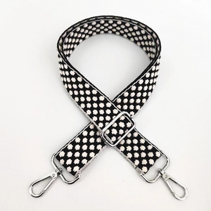 Close-up of black and white polka dot adjustable woven strap with silver metal hooks