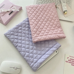 Quilted diamond pattern padded laptop sleeves in soft pink and purple on office desk