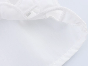 Gros plan sur la broderie française blanche et les détails ajourés du haut sans manches
