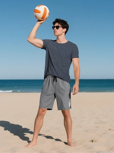 Men's blue slim fit athletic t-shirt and grey shorts outfit on a sunny beach setting