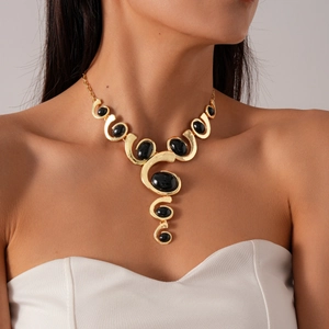 Collier spirale doré artistique avec pierres noires ovales porté sur mannequin de mode
