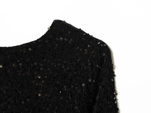 Close-up of black sequins and stitching details on the neckline of a women's top