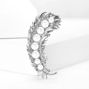 Detailed close-up of a silver feather brooch with elegant pearls on a white background