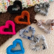 Detail of wool-wrapped heart hair clips in vibrant colors and knitted textures