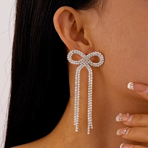 Gros plan de boucles d'oreilles nœud scintillant avec longs glands sur un modèle