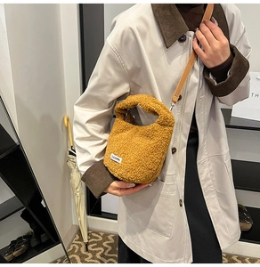 Detail of ginger plush lamb wool crossbody bucket bag with white fabric label and strap