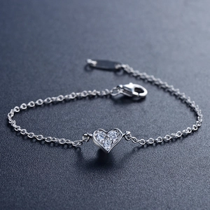 Sparkling S925 sterling silver heart bracelet with three inlaid zircons on a dark background