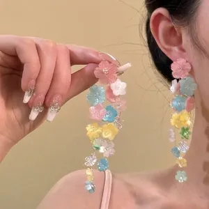 Detailed view of colorful multi-layer floral tassel earrings on model in warm studio light