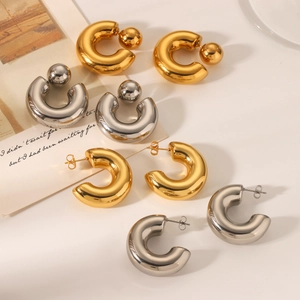 Polished gold and silver C-shaped chunky earrings with metal bead details on beige base