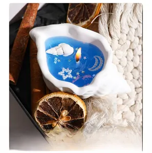 Close-up of a burning conch-shaped aromatherapy candle with blue wax and pearls