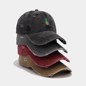 Detailed macro view showing distressed vintage texture and pineapple embroidery on caps