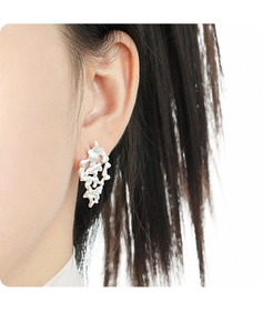 Macro view of silver lava-shaped irregular earring on ear with high-quality metallic texture