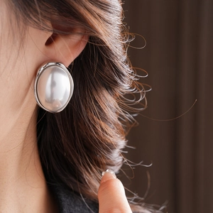 Close-up of model wearing large oval pearl earrings with silver metallic vintage frame