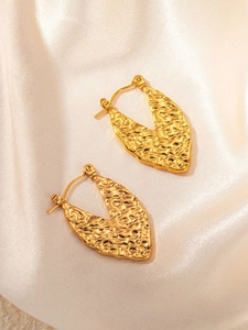 Close-up of golden hammered texture hoop earrings on luxury champagne silk fabric