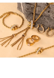 Detailed shot of gold necklace and earring set with tassels and crystals on stone