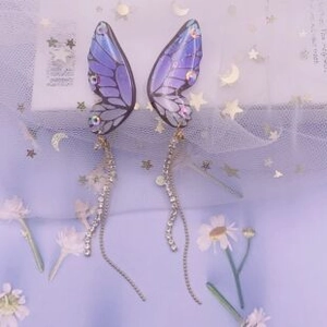 Detailed macro of gradient purple butterfly wing earrings with long silver tassels