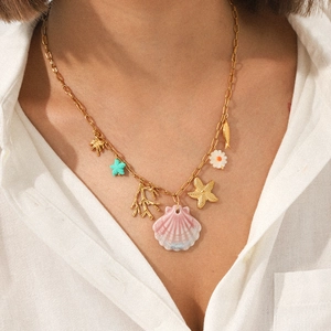 Detail of a gold starfish necklace with colorful shell and coral charms on a model