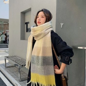 Winter plaid scarf with tassels in beige grey and yellow, worn in an outdoor street setting