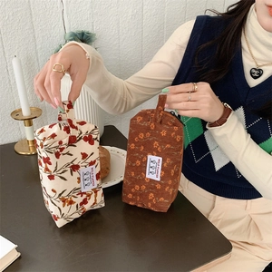 Détail de trousses à maquillage en velours côtelé avec imprimé floral et étiquette wild flower