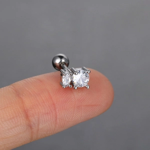 Close-up of geometric silver cartilage piercing with clear round and oval zircon stones