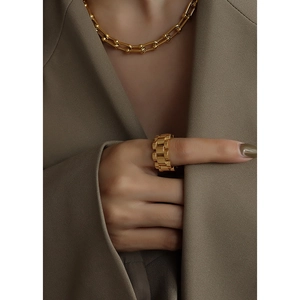 Golden watch-band style wide ring and bold link chain necklace on a blazer model