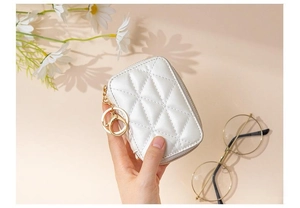 Close-up of white quilted cosmetic bag with gold keychain and secure zipper closure