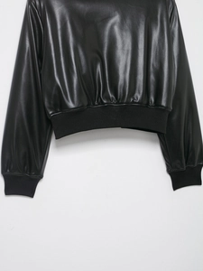Close-up of ribbed cuffs and hem on a black coated faux leather bomber jacket