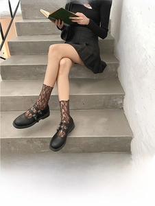Dettagli di scarpe Mary Jane nere con cinturino doppio e calzini in pizzo marrone retrò