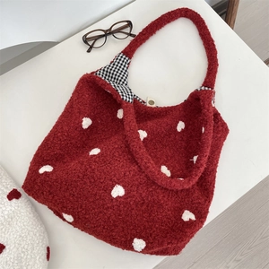 Detail view of a soft red fuzzy tote bag with embroidered white hearts and gingham lining
