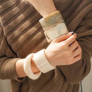 Close-up of vintage resin geometric cuff bracelet worn over a brown knit sweater